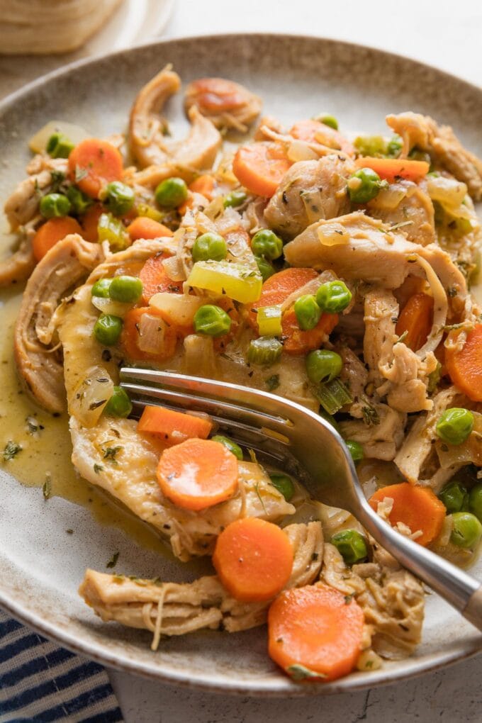 Close up of a fork pulling off a bite of creamy chicken and biscuits.
