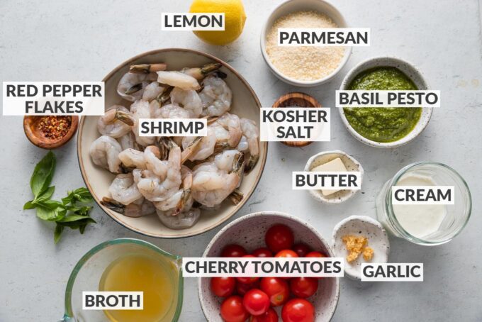 Labeled ingredient photo of shrimp, pesto, tomatoes, broth, cream, and spices.