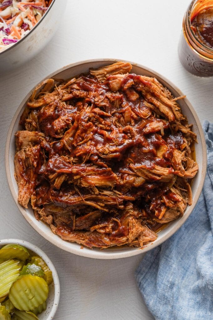 Bowl of shredded pork cooked in the slow cooker and topped with a rich, dark molasses-colored BBQ sauce.