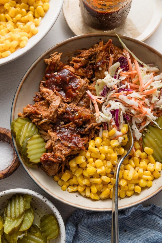BBQ pulled pork bowl with coleslaw, corn, and pickles.
