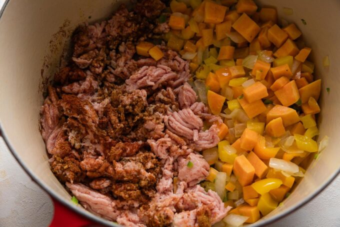 Ground turkey and spices added to one side of the Dutch oven with veggies pushed to the other side.
