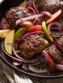 This cozy apple cider chicken skillet is surprisingly easy to make and basically delivers fall on a dinner plate! Pan-seared chicken thighs stay nice and juicy in a delicious pan sauce of fresh apple cider and a hint of Dijon, and they taste extra lovely with tender apple slices and tangy red onions. One pan and 30 minutes only!