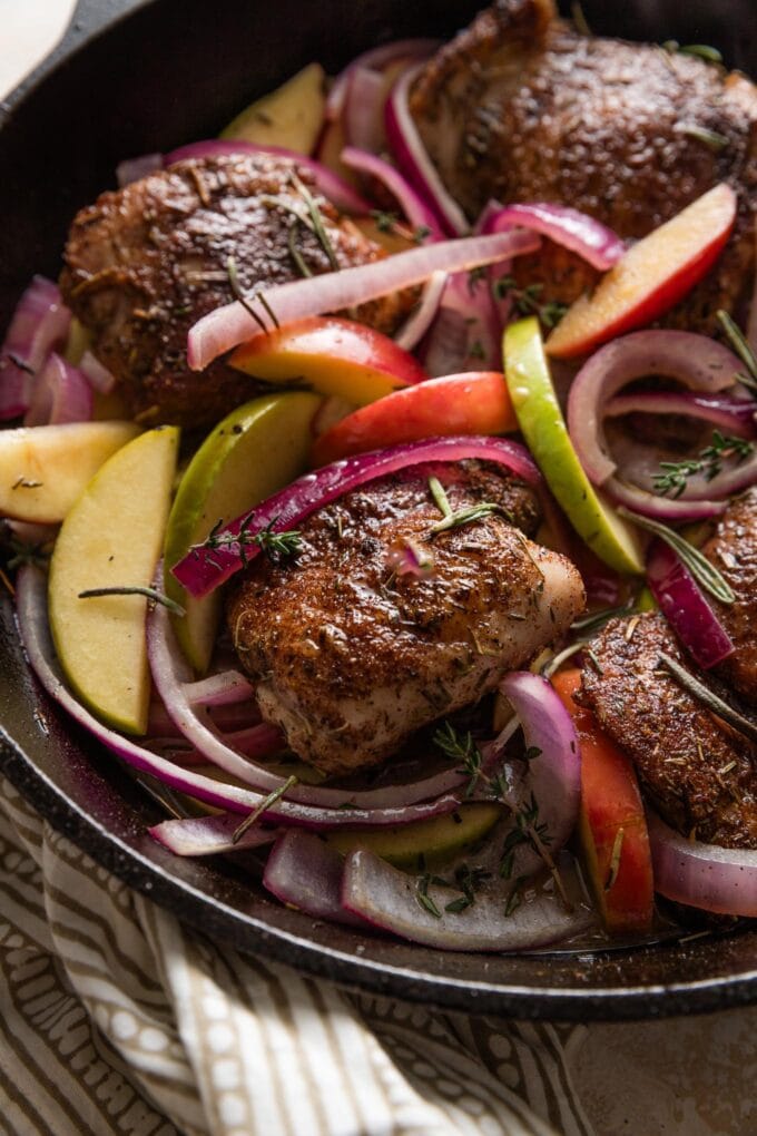 This cozy apple cider chicken skillet is surprisingly easy to make and basically delivers fall on a dinner plate! Pan-seared chicken thighs stay nice and juicy in a delicious pan sauce of fresh apple cider and a hint of Dijon, and they taste extra lovely with tender apple slices and tangy red onions. One pan and 30 minutes only!