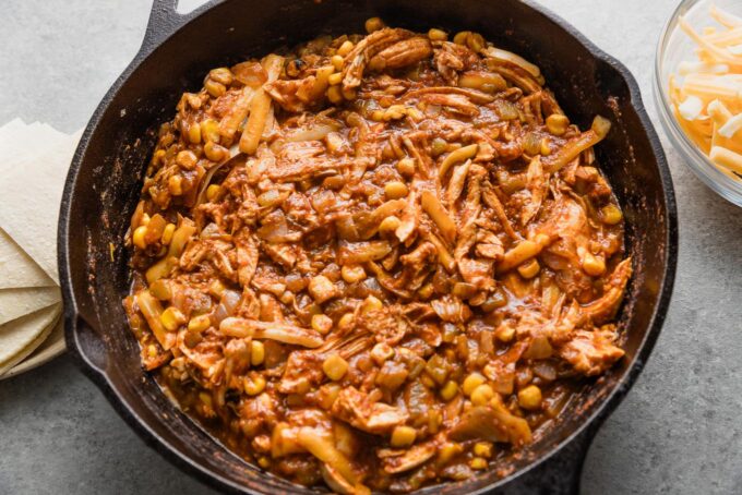 Chicken and enchilada sauce mixture blended in a skillet.