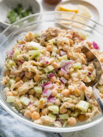 Large bowl full of tuna salad with chickpeas, red onion, celery, lemon, and fresh dill.
