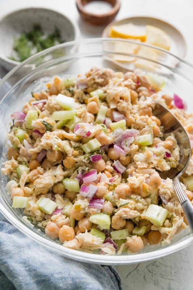 Large bowl full of tuna salad with chickpeas, red onion, celery, lemon, and fresh dill.