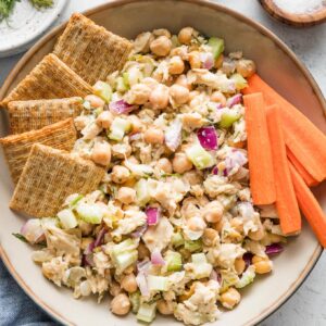 Bowl of tuna salad with chickpeas served with Triscuits and carrot sticks.