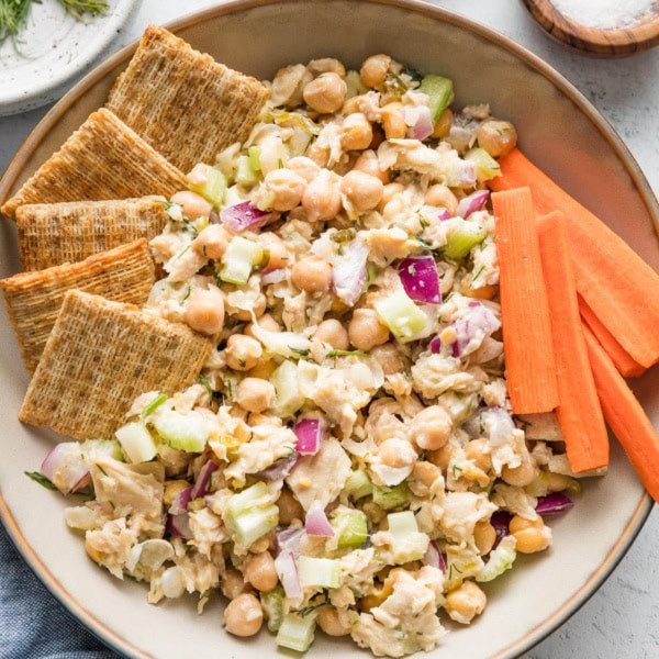 Bowl of tuna salad with chickpeas served with Triscuits and carrot sticks.