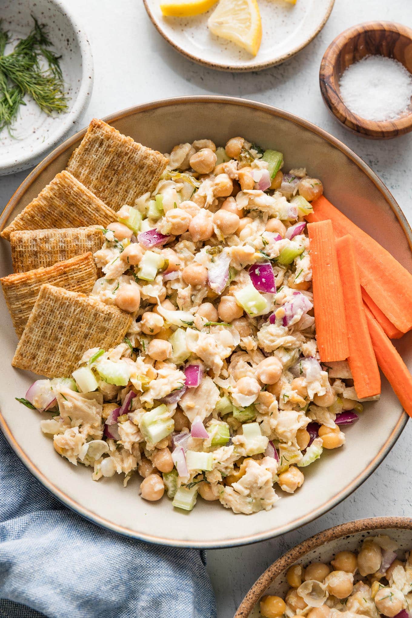 Bowl of tuna salad with chickpeas served with Triscuits and carrot sticks.