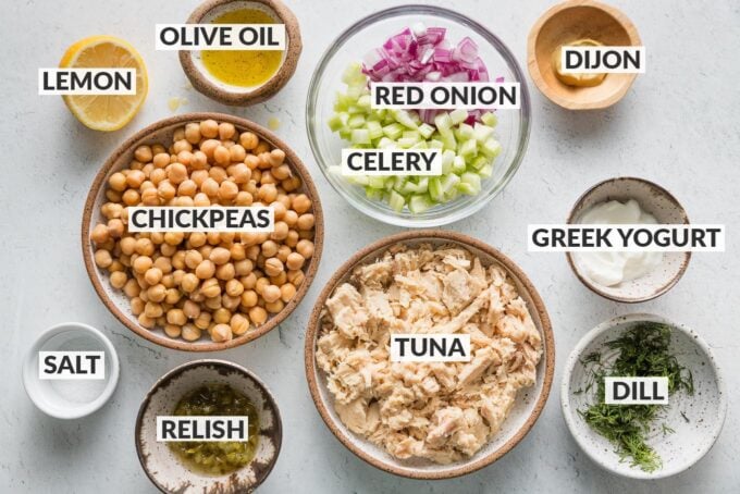 Labeled overhead photo of drained and rinsed canned chickpeas, drained tuna, chopped celery and red onion, fresh dill, olive oil, lemon, Greek yogurt, Dijon mustard, salt, and relish.