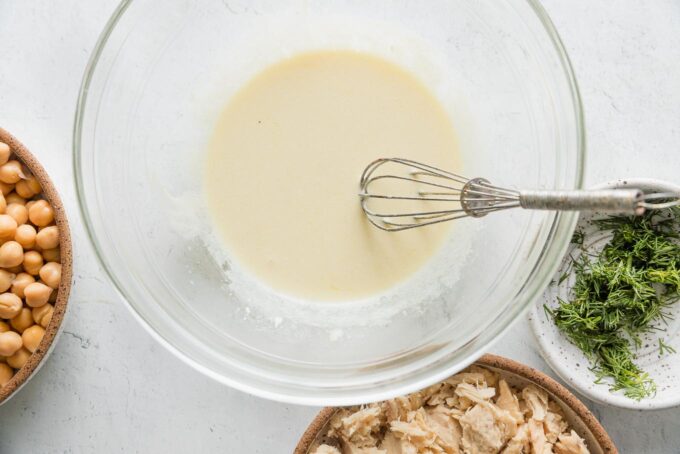 Quick tuna salad dressing whisked together in a large glass bowl.
