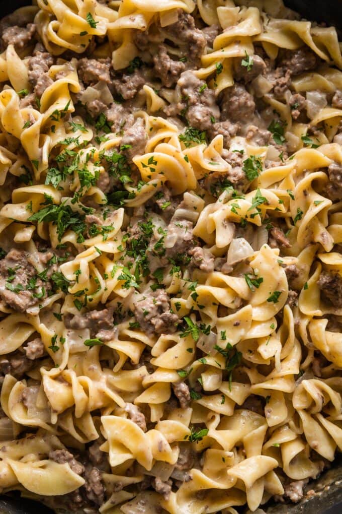 Close up of ground beef and noodles sprinkled with fresh chopped Italian parsley.
