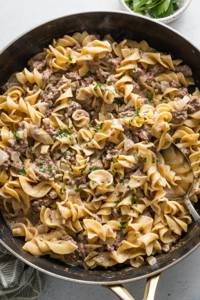 Large saute pan filled with an easy dinner of ground beef and noodles in a homemade cream sauce.