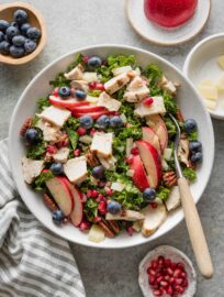 Forkful of kale apple salad with chicken and berries in a light lemon olive oil dressing.