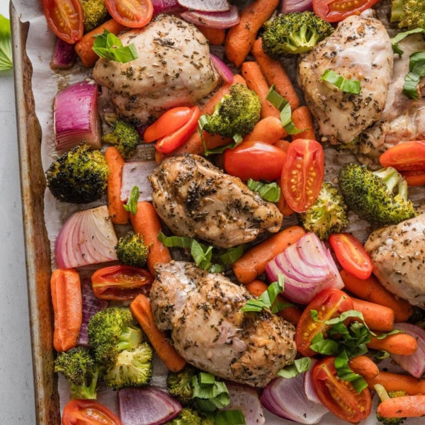 Large rimmed sheet pan filled with roasted balsamic chicken thighs and assorted veggies.