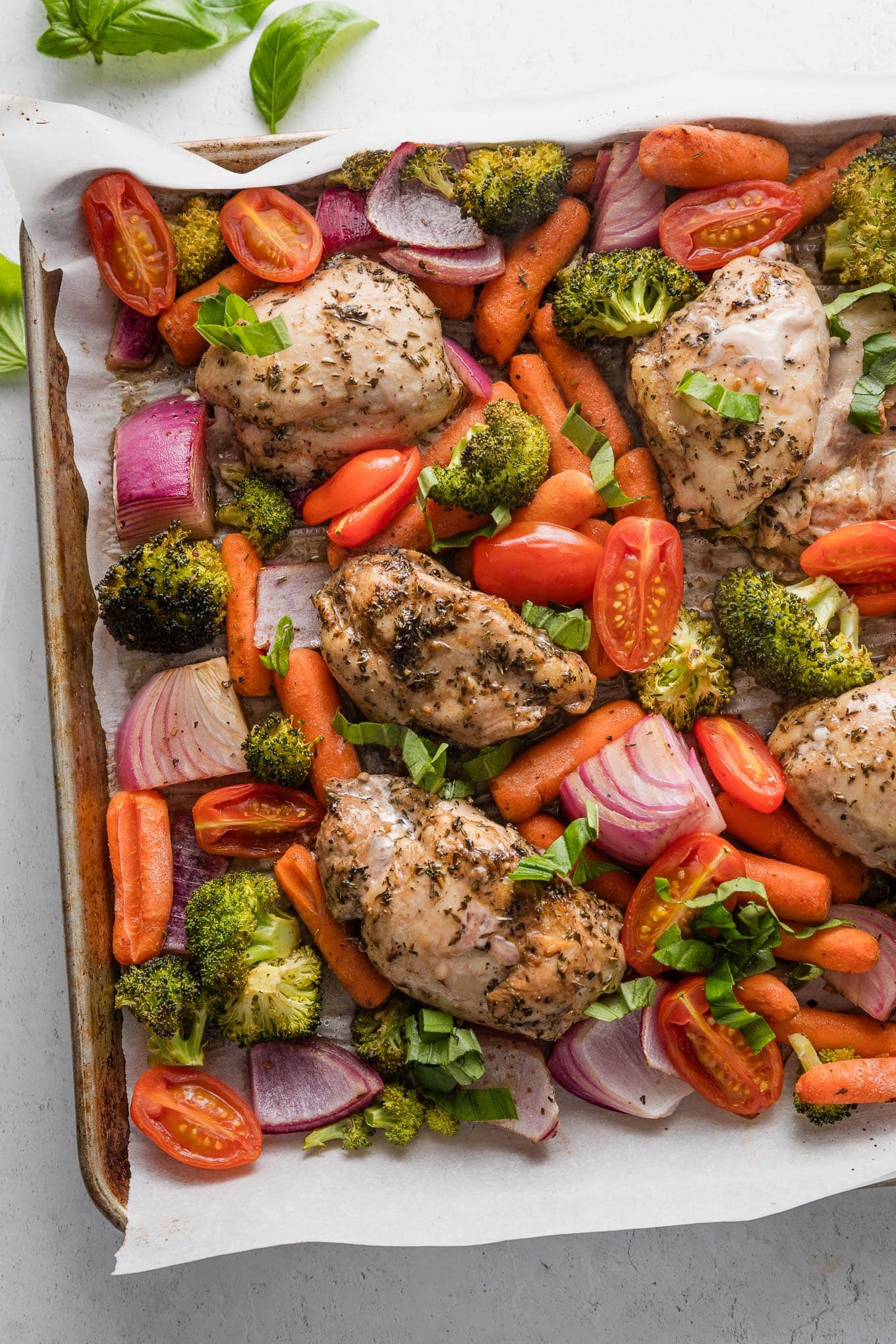 Large rimmed sheet pan filled with roasted balsamic chicken thighs and assorted veggies.