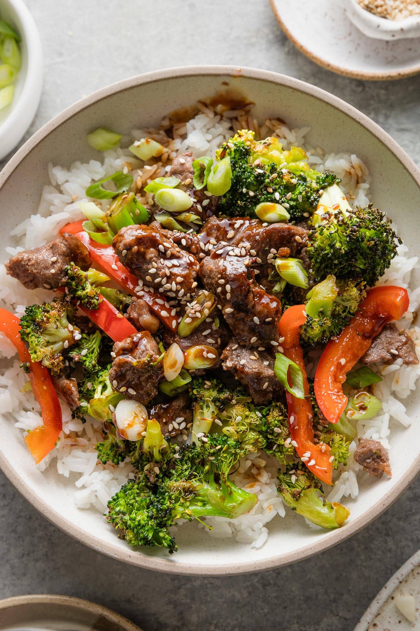 Bowl of marinated sirloin tips served with roasted broccoli and red bell peppers.
