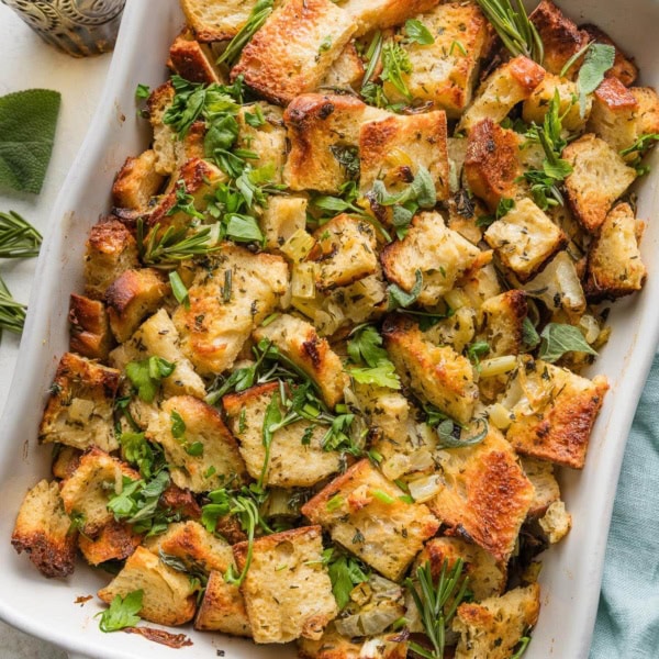 Large baking pan full of bread stuffing with butter and herbs.