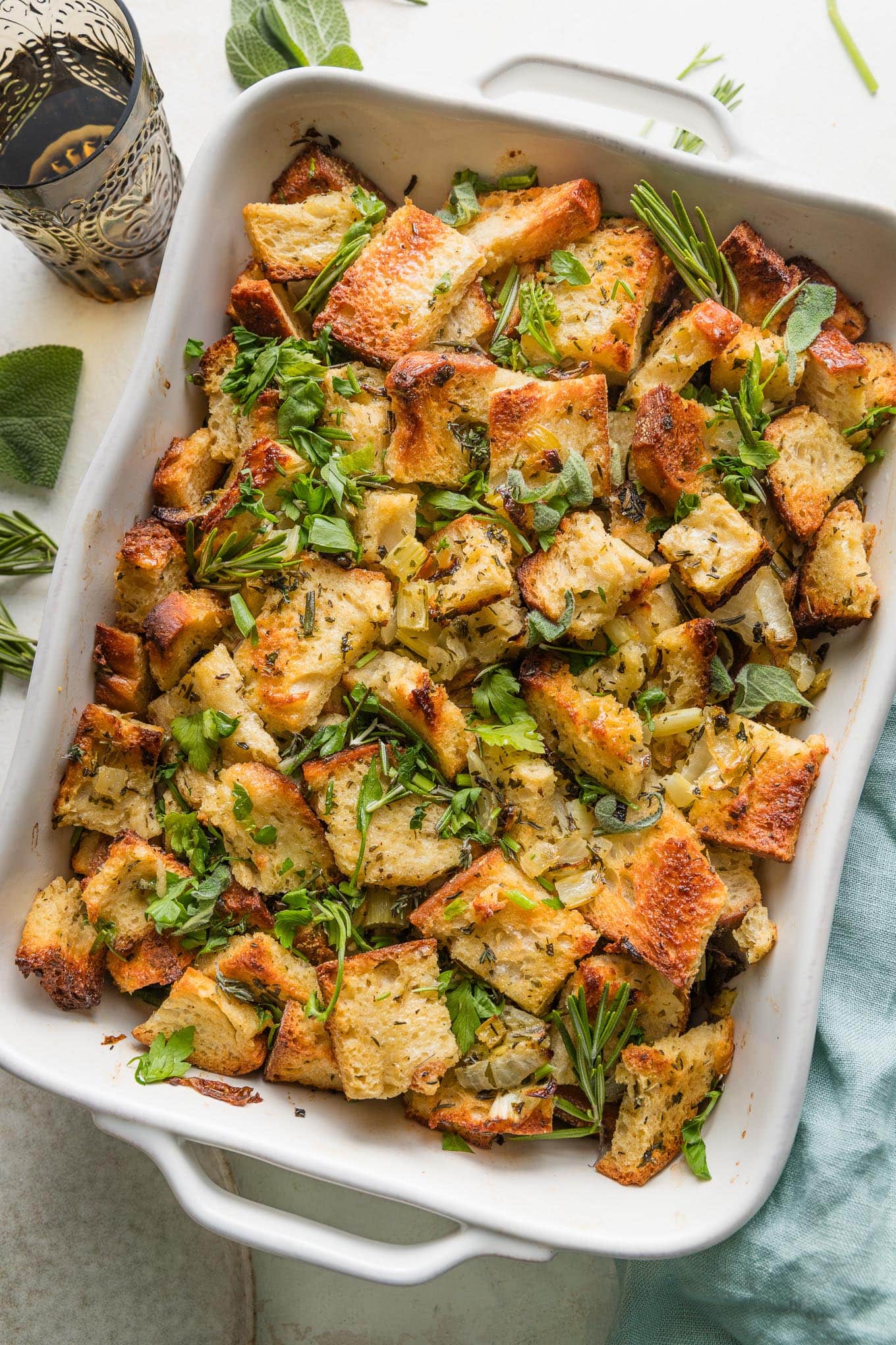 Large baking pan full of bread stuffing with butter and herbs.