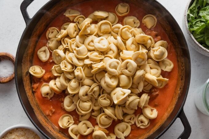 Fresh tortellini added to skillet with sausage and tomato cream sauce.