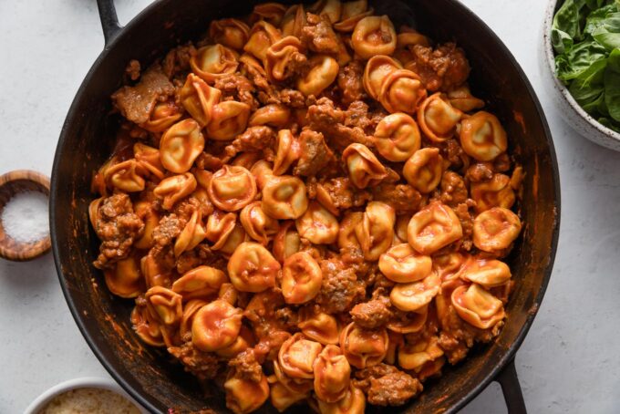 Tortellini cooked directly in tomato sauce in a deep cast iron skillet.