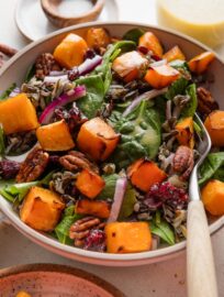 Large fork picking up a bite of wild rice salad with butternut squash and baby spinach.