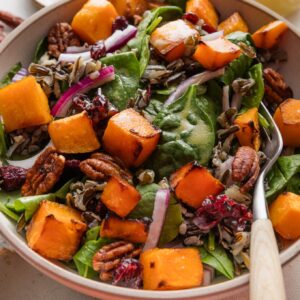 Large fork picking up a bite of wild rice salad with butternut squash and baby spinach.