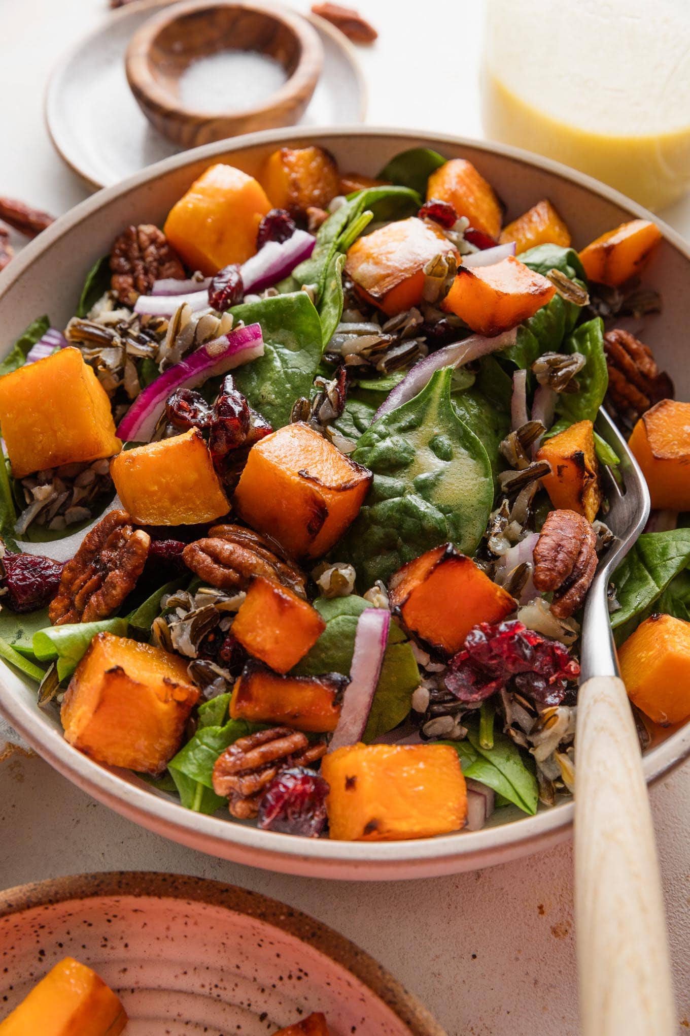 Large fork picking up a bite of wild rice salad with butternut squash and baby spinach.