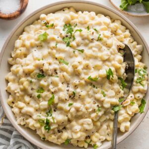 Bowl of creamed corn sprinkled with finely chopped fresh parsley.