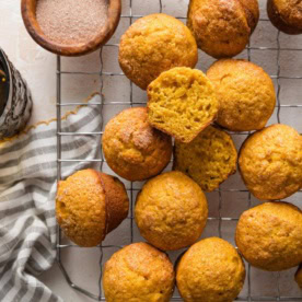 Cooling rack full of miniature pumpkin muffins with a cinnamon sugar topping.