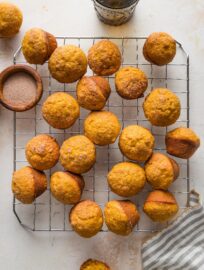 Countertop with a pretty napkin and a small wire cooling rack full of mini pumpkin muffins.