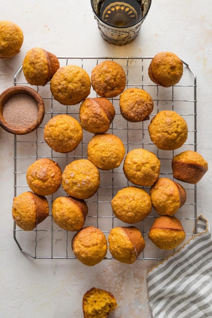 Countertop with a pretty napkin and a small wire cooling rack full of mini pumpkin muffins.