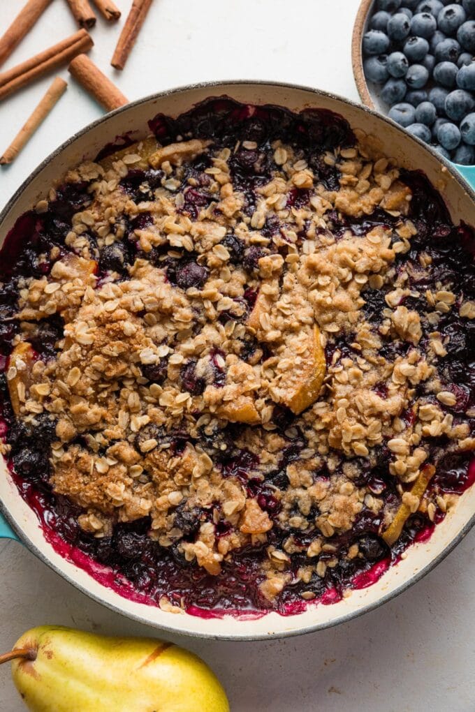 Overhead view of a blueberry pear crisp just baked in an enameled cast iron skillet.