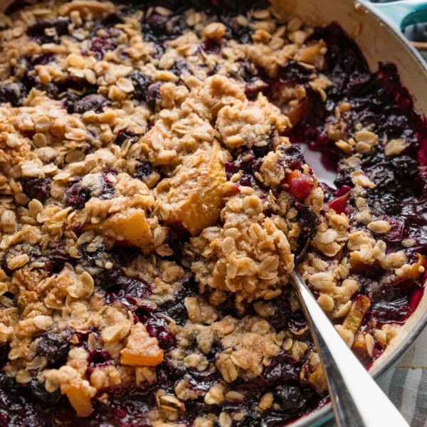 Close up of a blueberry and pear crisp with oat crumble topping served piping hot out of an oven safe skillet.