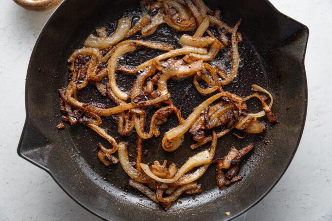 Caramelized onions resting in a cast iron pan.