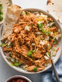 Instant Pot shredded Mexican chicken with salsa served over a Southwestern style salad kit with a tortilla on the side.