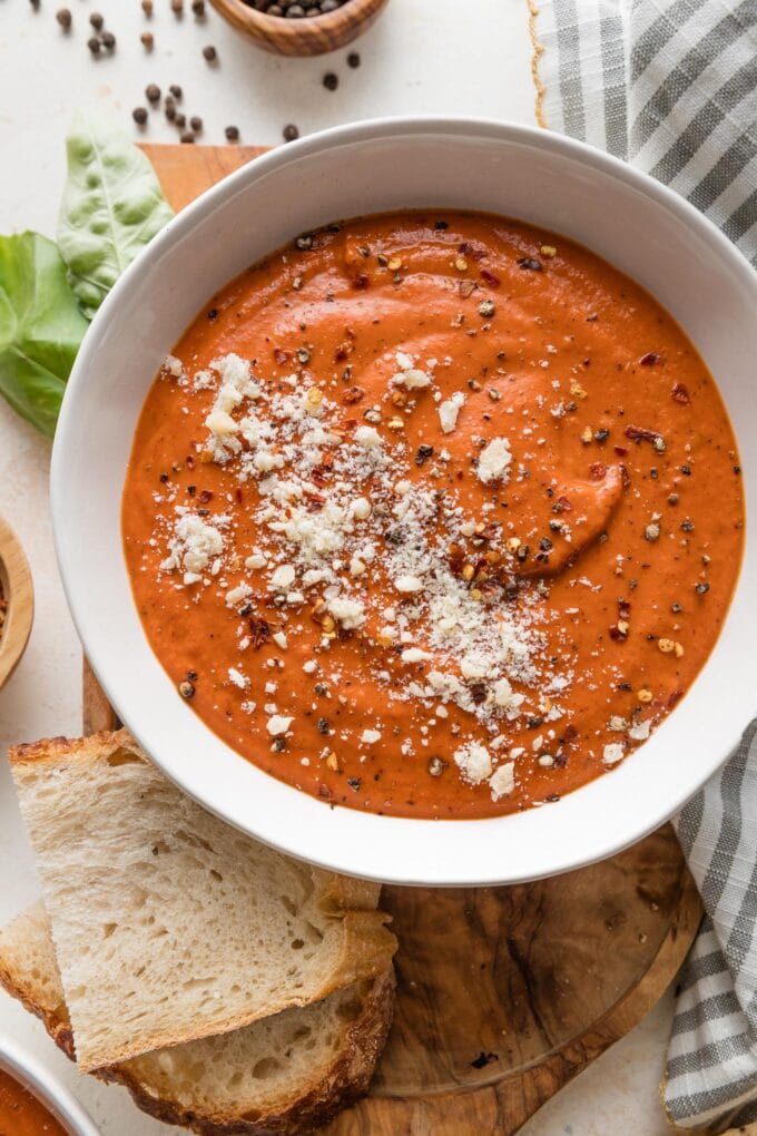 Bowl of velvety, rich tomato butternut bisque with fresh basil and thick-cut sourdough toast nearby.