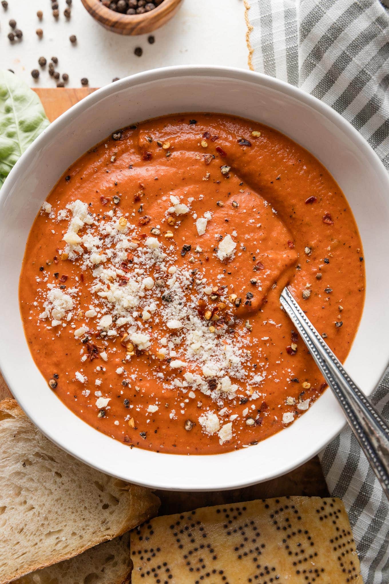 Bowl of tomato bisque with butternut squash garnished with a generous sprinkle of Parmesan cheese and fresh-cracked black pepper.