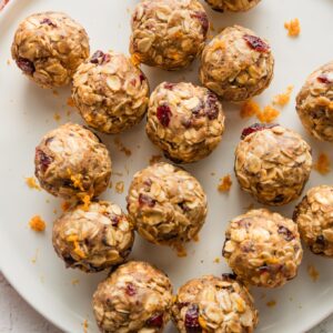 Small plate full of small protein bites flavored with dried cranberries, orange, maple syrup, and cinnamon.