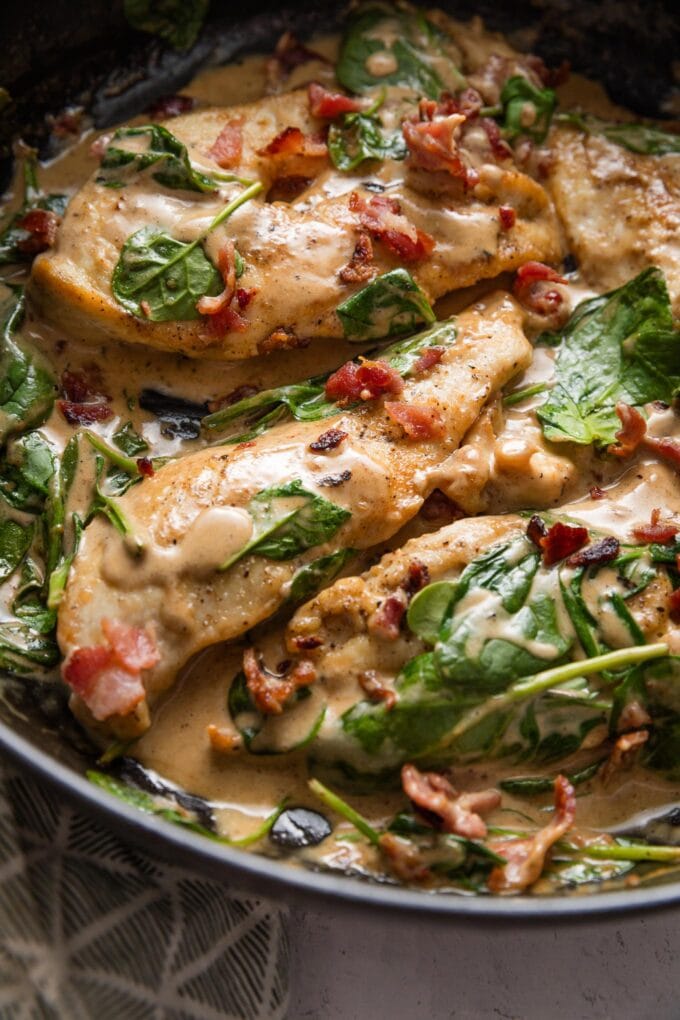 Close up of balsamic chicken with spinach and bacon in a deep cast iron skllet.