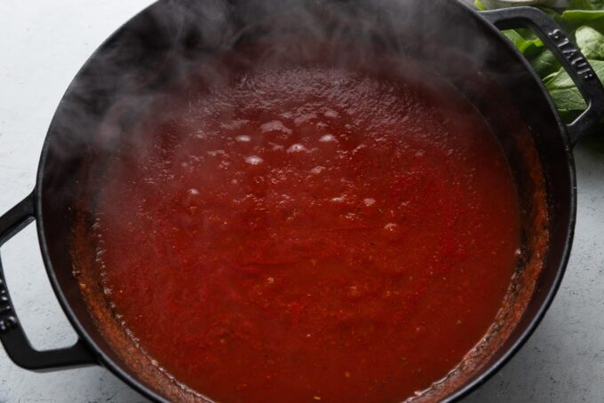 Deep cast iron skillet filled with a quick homemade tomato sauce.