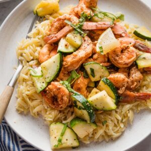Plate of paprika-seasoned, oven-roasted shrimp and zucchini served on a plate over orzo.