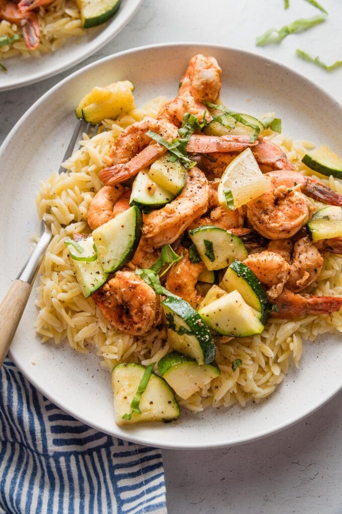 Plate of paprika-seasoned, oven-roasted shrimp and zucchini served on a plate over orzo.