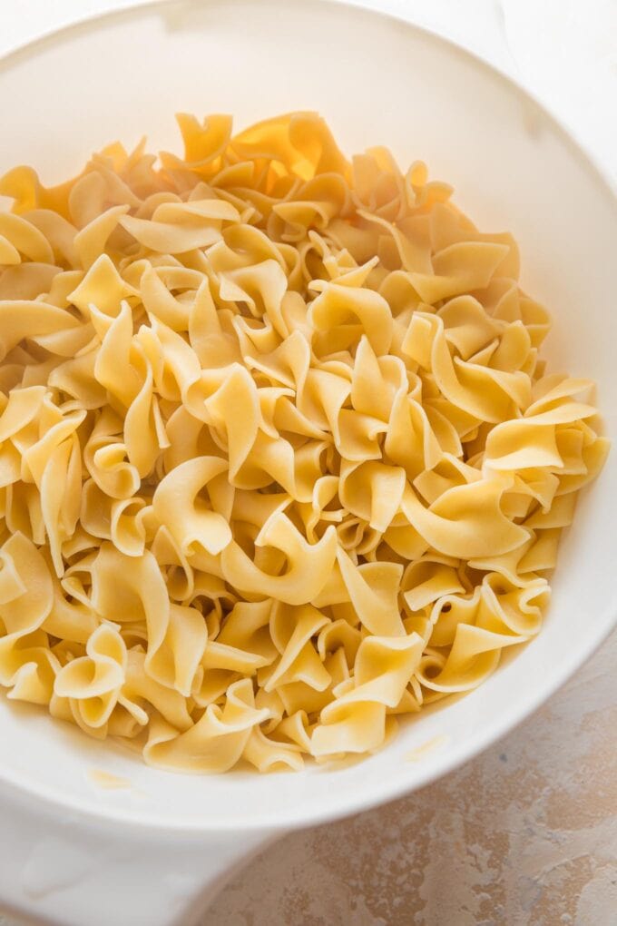 Drained egg noodles cooling in a colander.