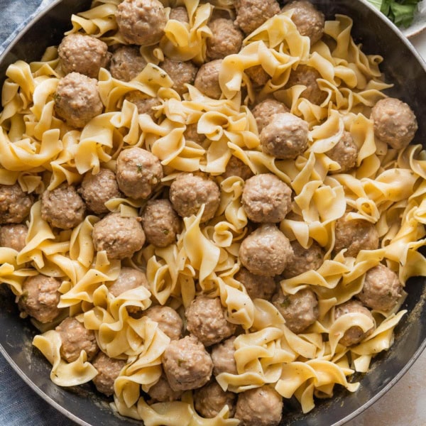 Large skillet full of quick Swedish meatballs with sauce and egg noodles.
