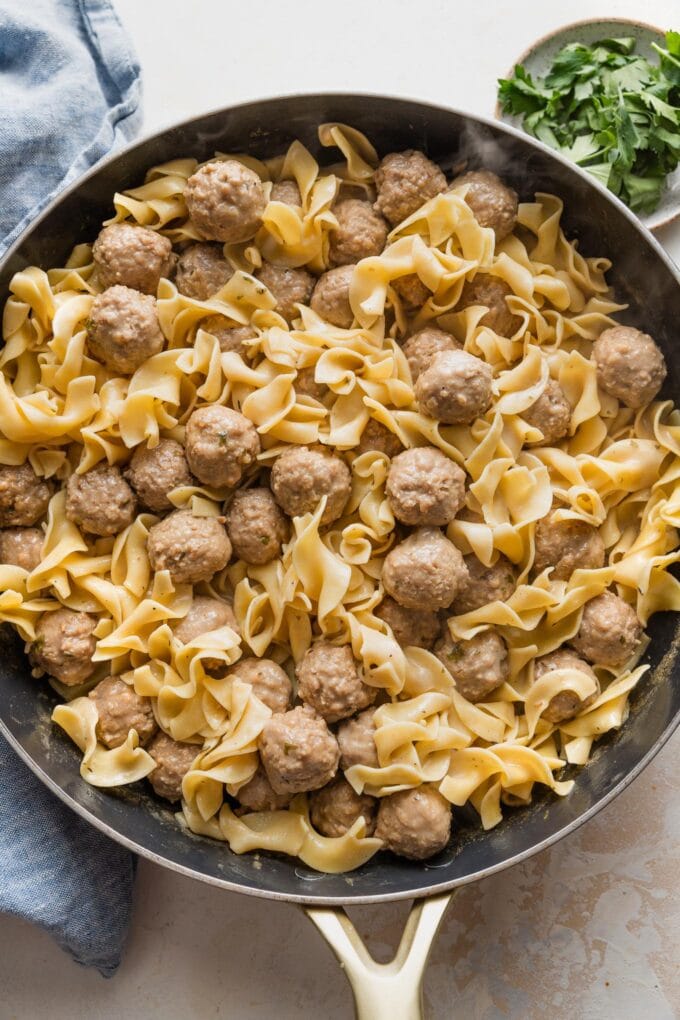 Large skillet full of quick Swedish meatballs with sauce and egg noodles.