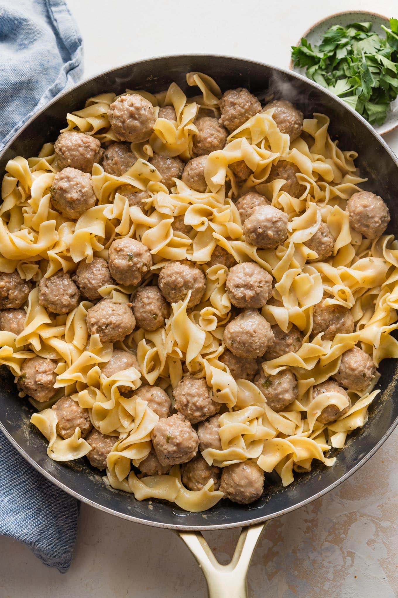 Large skillet full of quick Swedish meatballs with sauce and egg noodles.