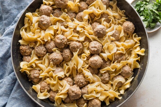 Large skillet full of quick Swedish meatballs with sauce and egg noodles.