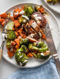 Sheet pan chipotle chicken thighs served with sweet potato, broccoli, and a simple lime crema.