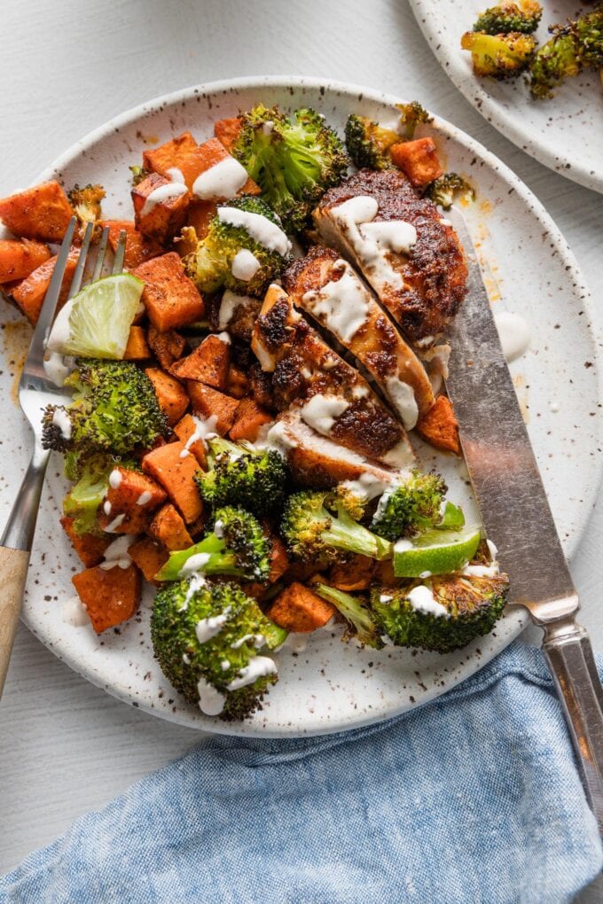 Sheet pan chipotle chicken thighs served with sweet potato, broccoli, and a simple lime crema.